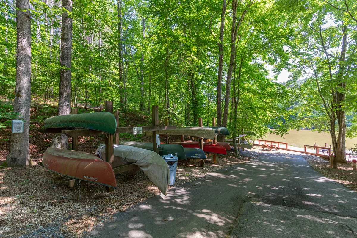 Colorful kayaks rest on a waterfront dock, flanked by trees, highlighting both the proximity to water and the sense of adventure awaiting outside the cabin. The setting exudes a relaxed and active lifestyle vibe.